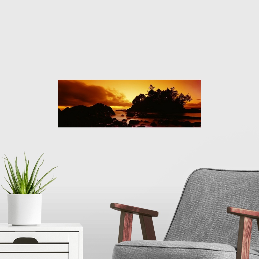 A modern room featuring Panoramic photograph displays a sunburnt sky as the sun begins to set over the profile of a rocky...