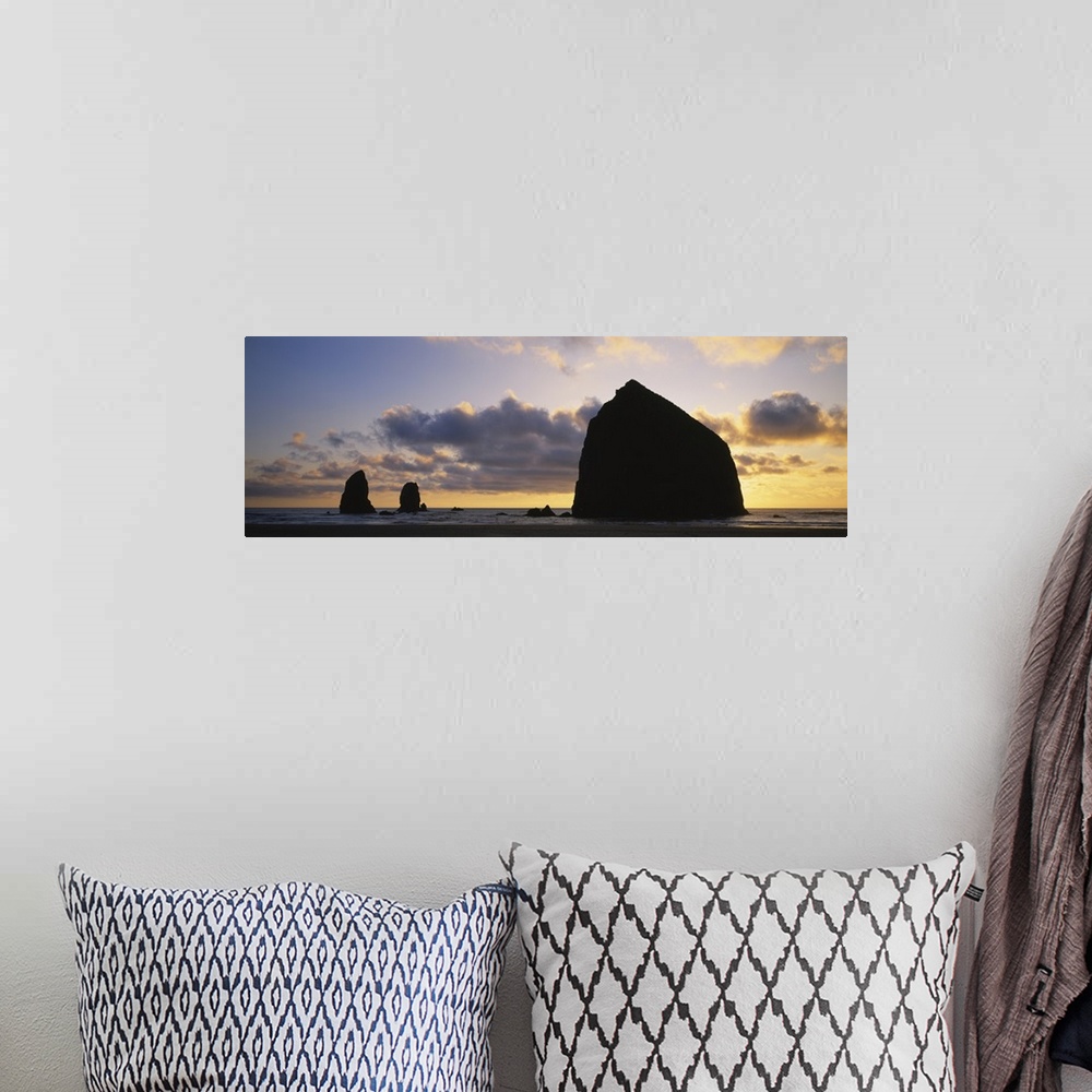 A bohemian room featuring Large panoramic piece of the sunset that silhouettes rock formations in the ocean.
