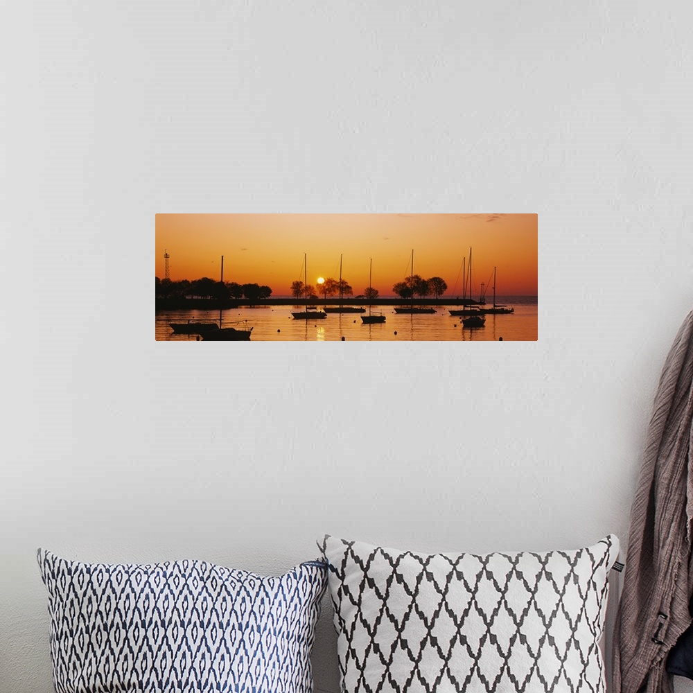 A bohemian room featuring This is a panoramic photograph of boats floating in a harbor as the sunsets reflecting off the wa...