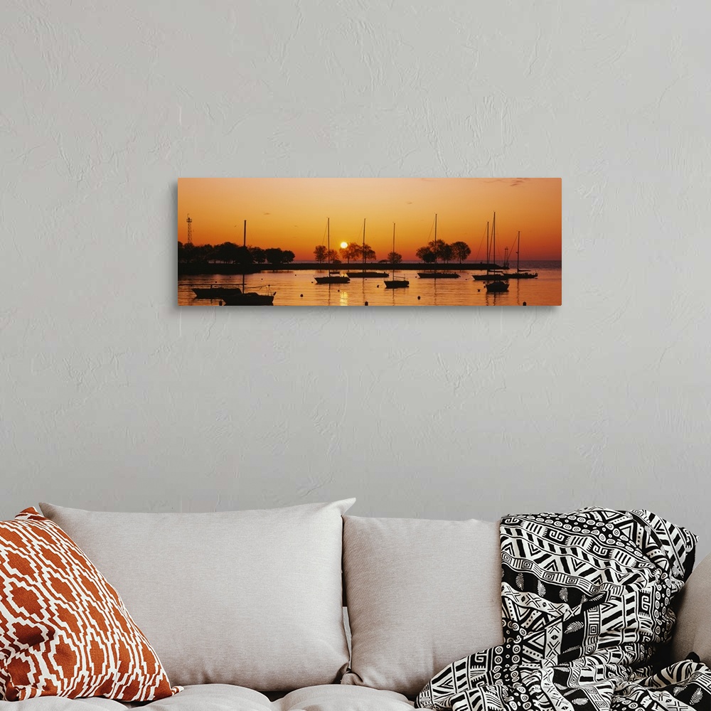 A bohemian room featuring This is a panoramic photograph of boats floating in a harbor as the sunsets reflecting off the wa...