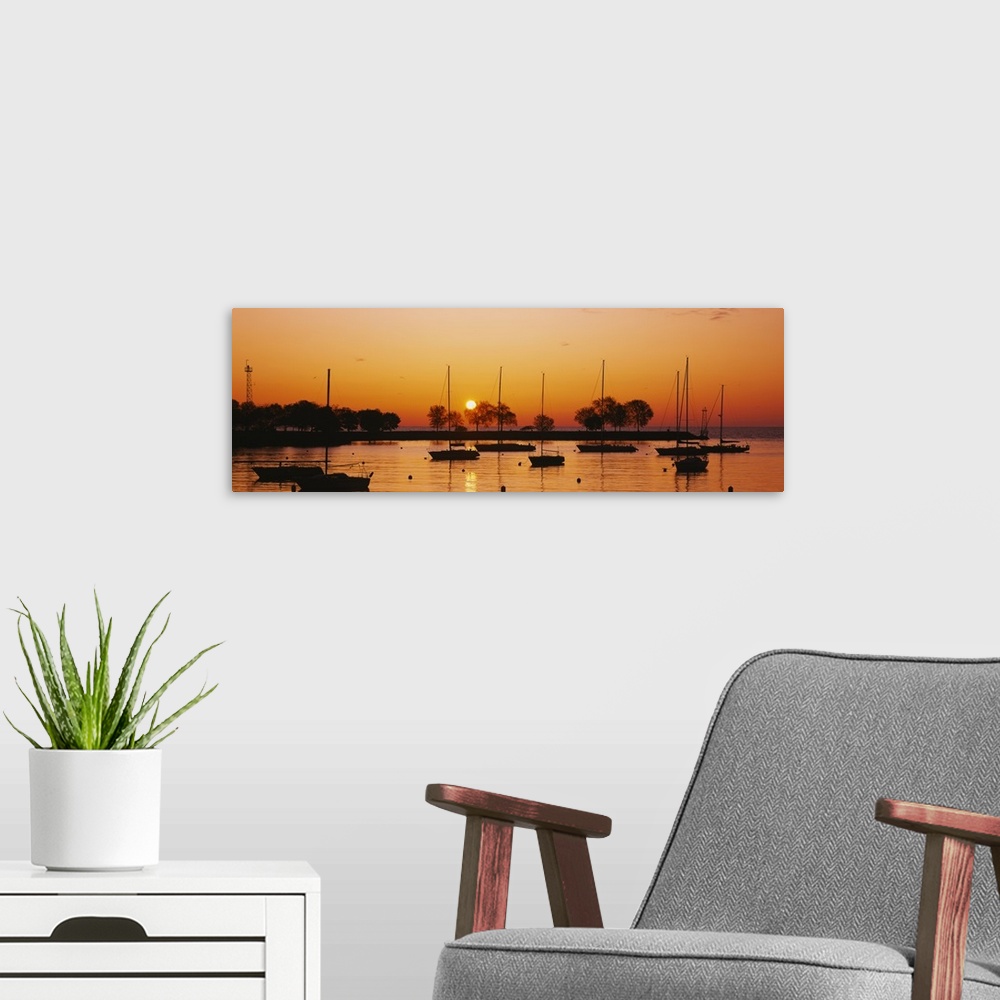 A modern room featuring This is a panoramic photograph of boats floating in a harbor as the sunsets reflecting off the wa...