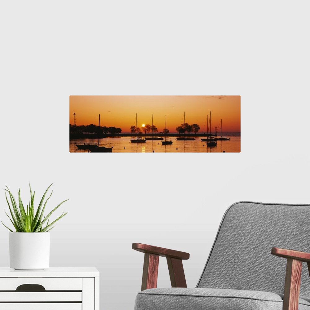A modern room featuring This is a panoramic photograph of boats floating in a harbor as the sunsets reflecting off the wa...