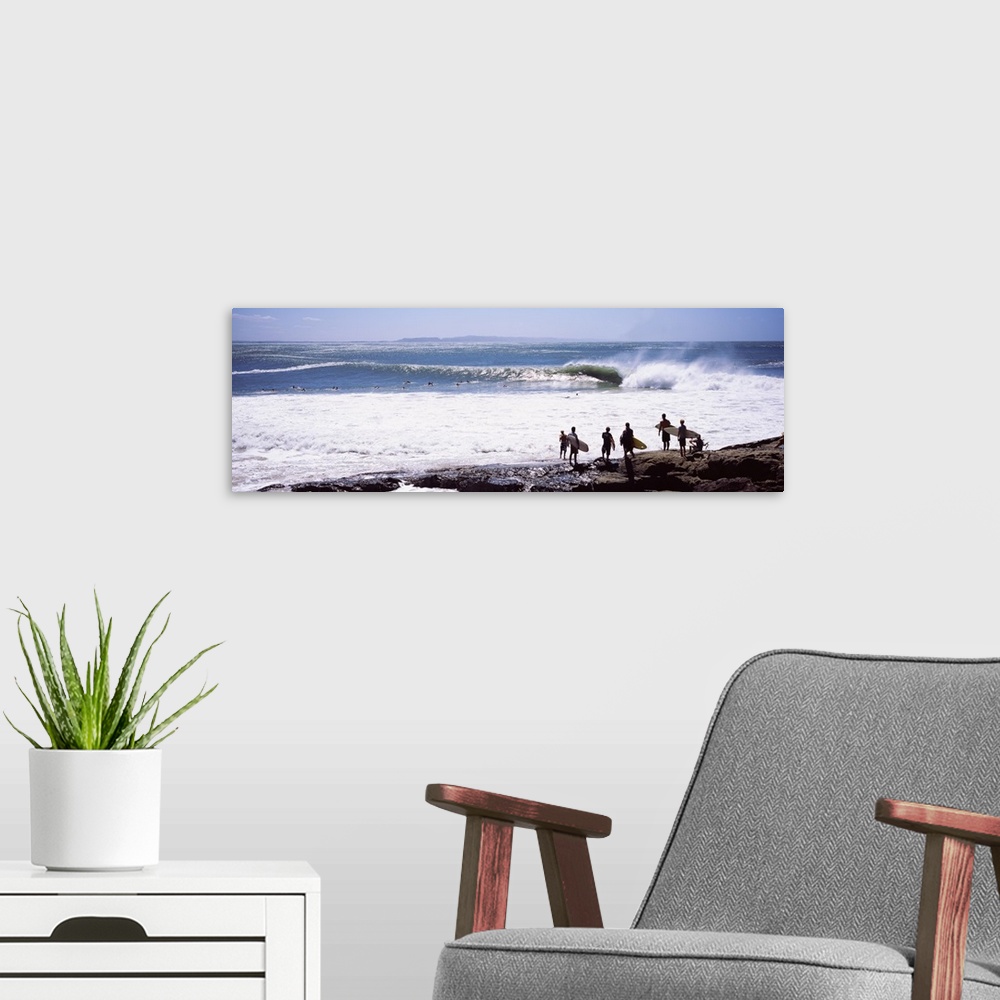 A modern room featuring Panoramic photograph of beachgoers at water's edge with waves and ocean in the distance.