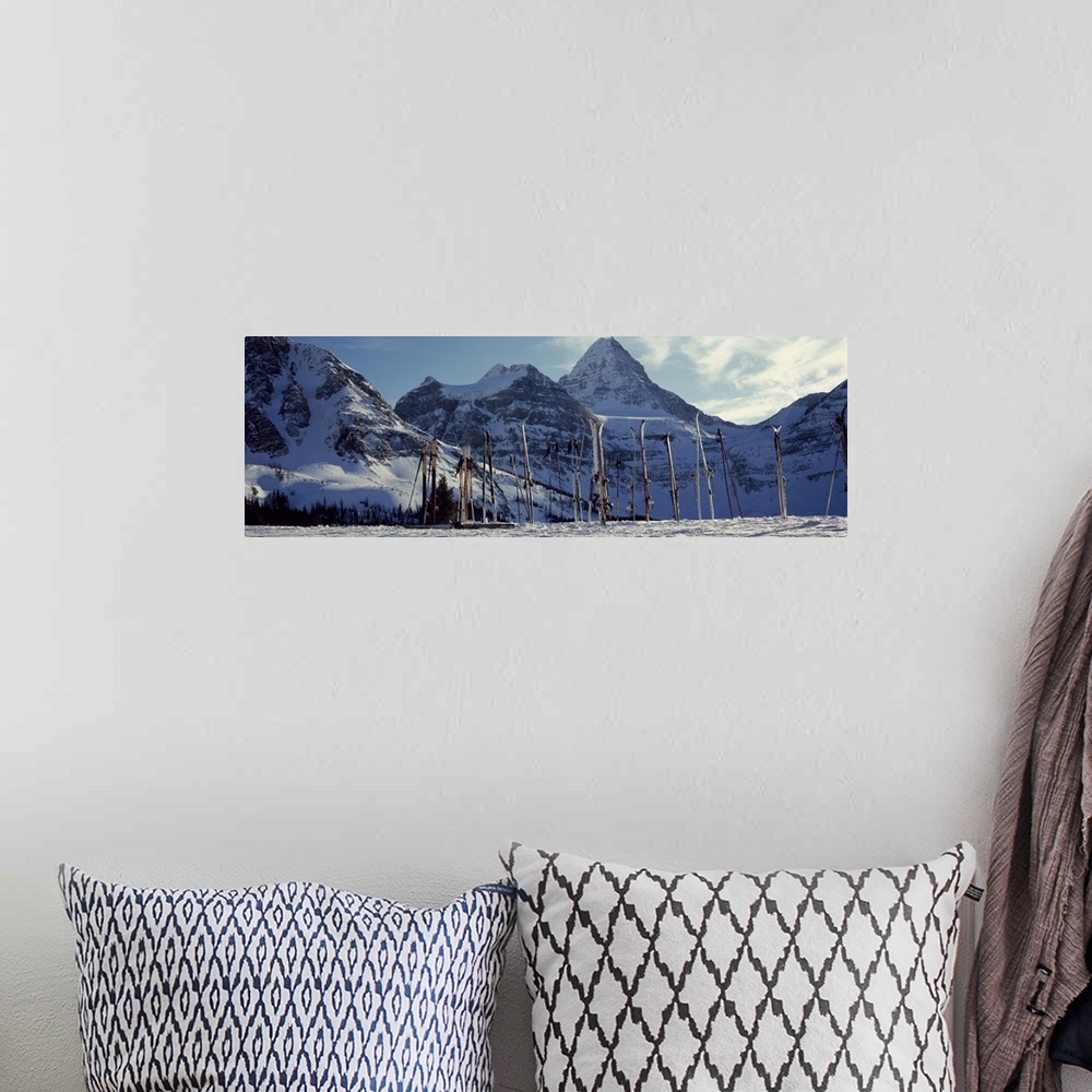 A bohemian room featuring Panoramic photo canvas of snowy mountains in the distance and ski equipment sticking out of the s...