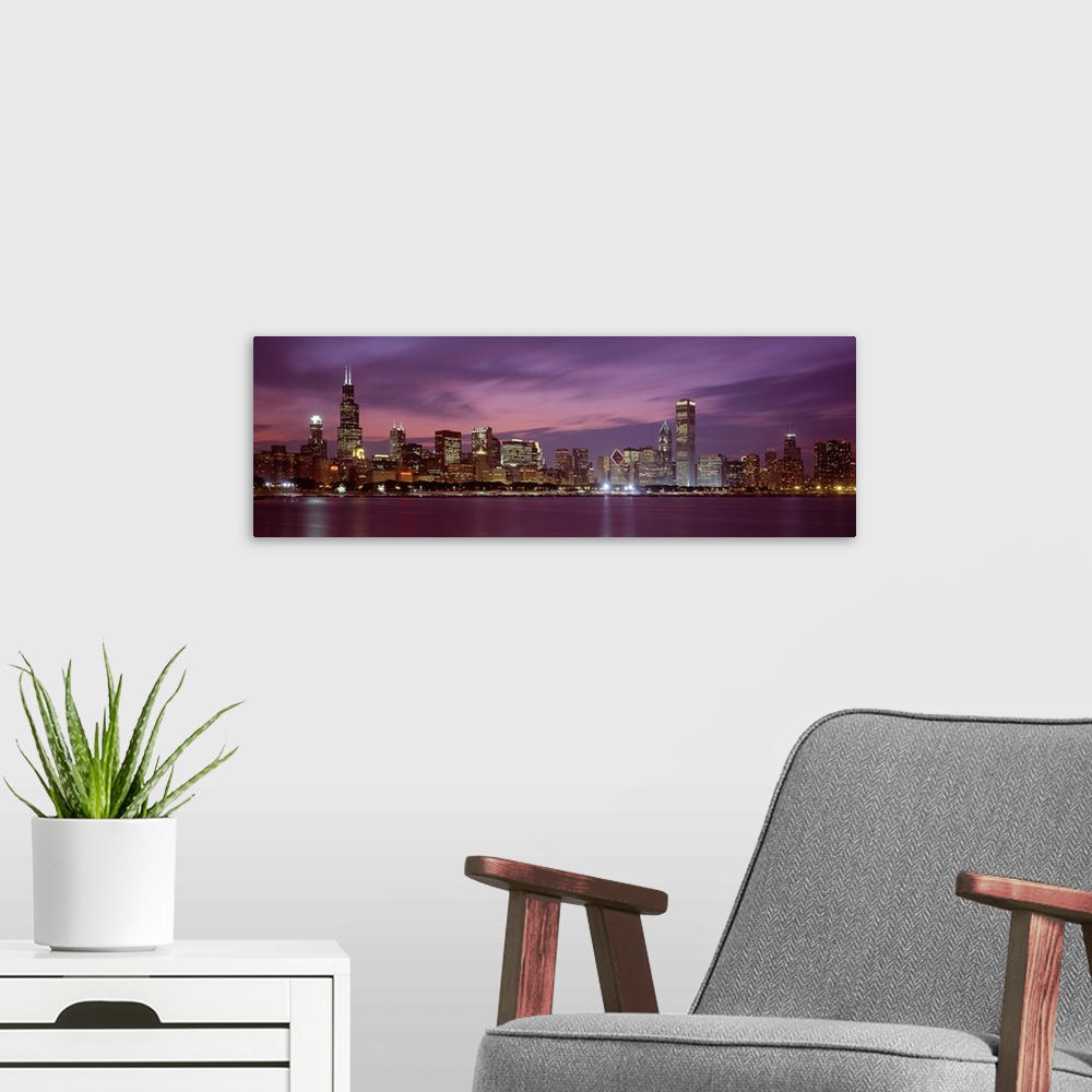 A modern room featuring Panoramic photograph displays a horizon filled with tall skyscrapers and buildings at nighttime f...