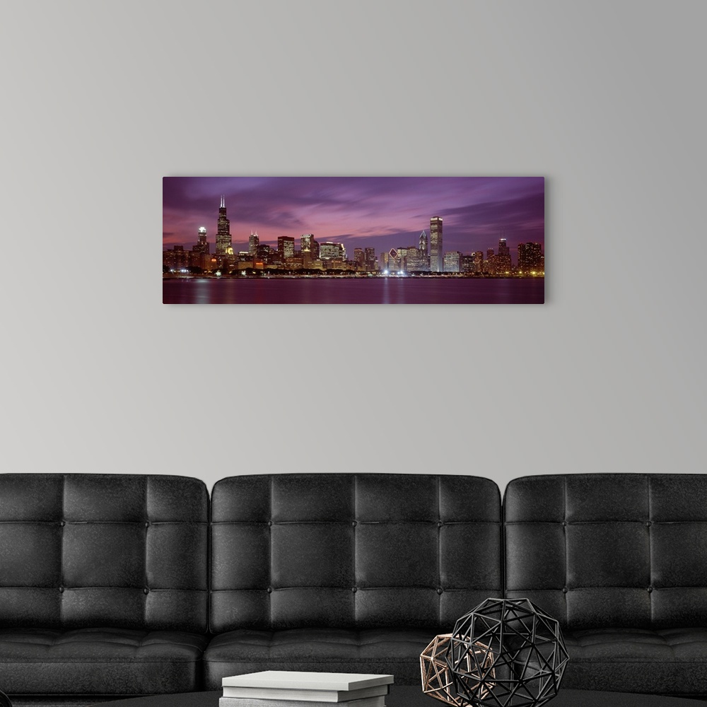 A modern room featuring Panoramic photograph displays a horizon filled with tall skyscrapers and buildings at nighttime f...