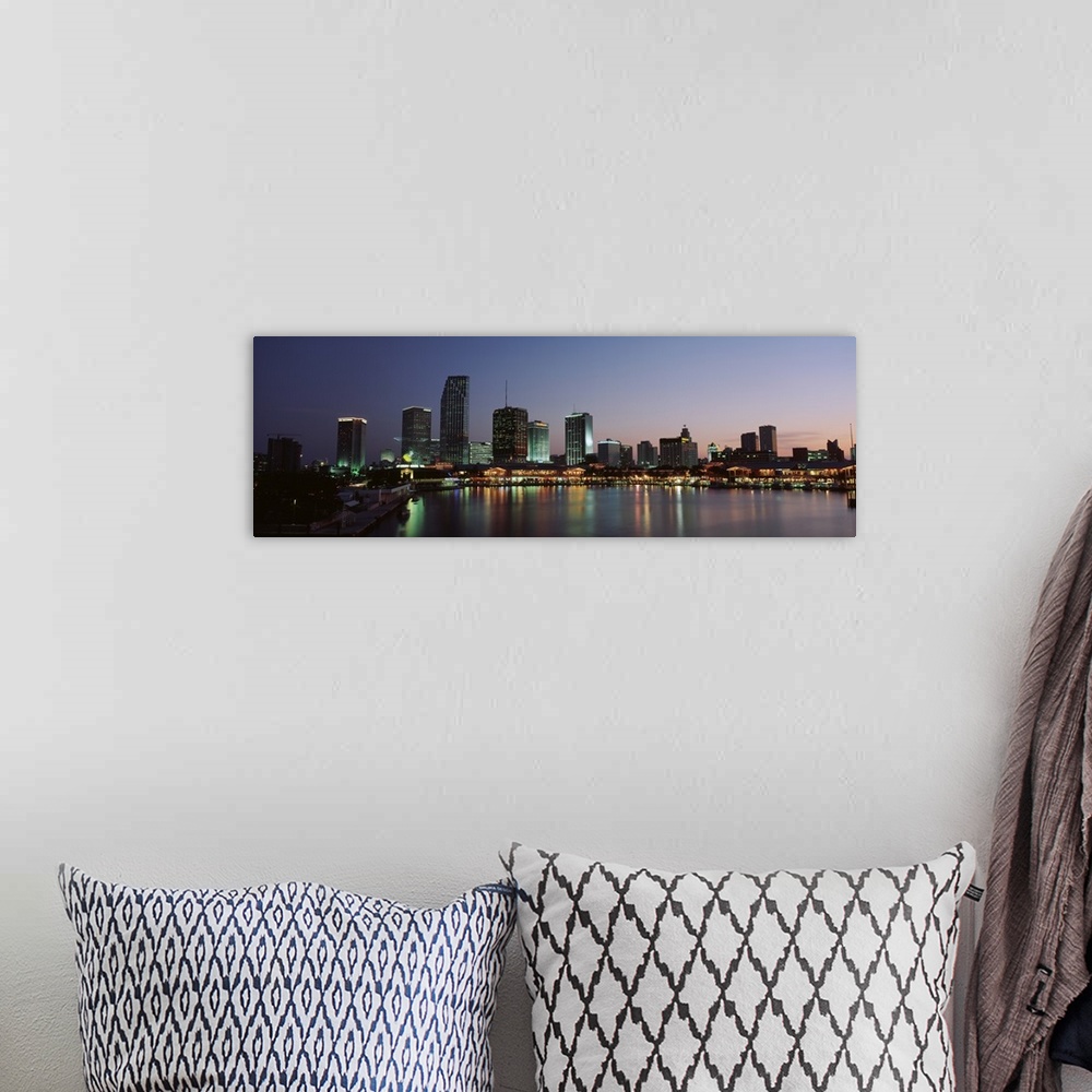 A bohemian room featuring Long print of a cityscape along the water in Florida lit up at dusk.