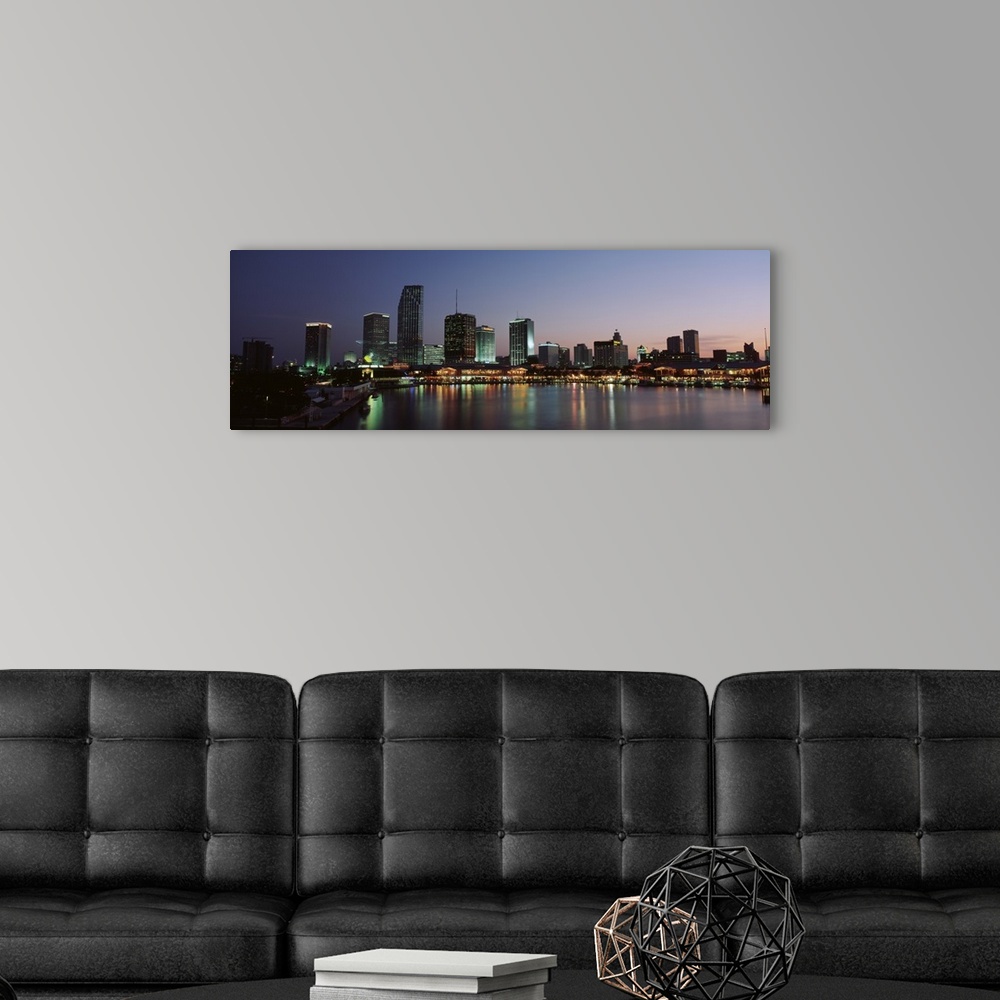 A modern room featuring Long print of a cityscape along the water in Florida lit up at dusk.