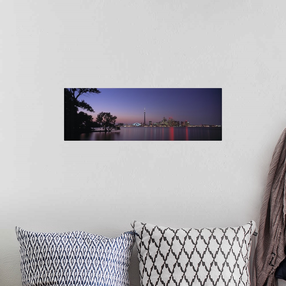 A bohemian room featuring A panoramic photograph taken at twilight of the city skyline in the distance reflecting in the wa...