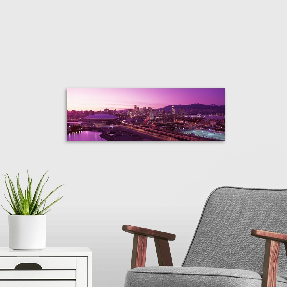 A modern room featuring An aerial panoramic photograph taken of the skyline in Vancouver that has a purple hue from the s...