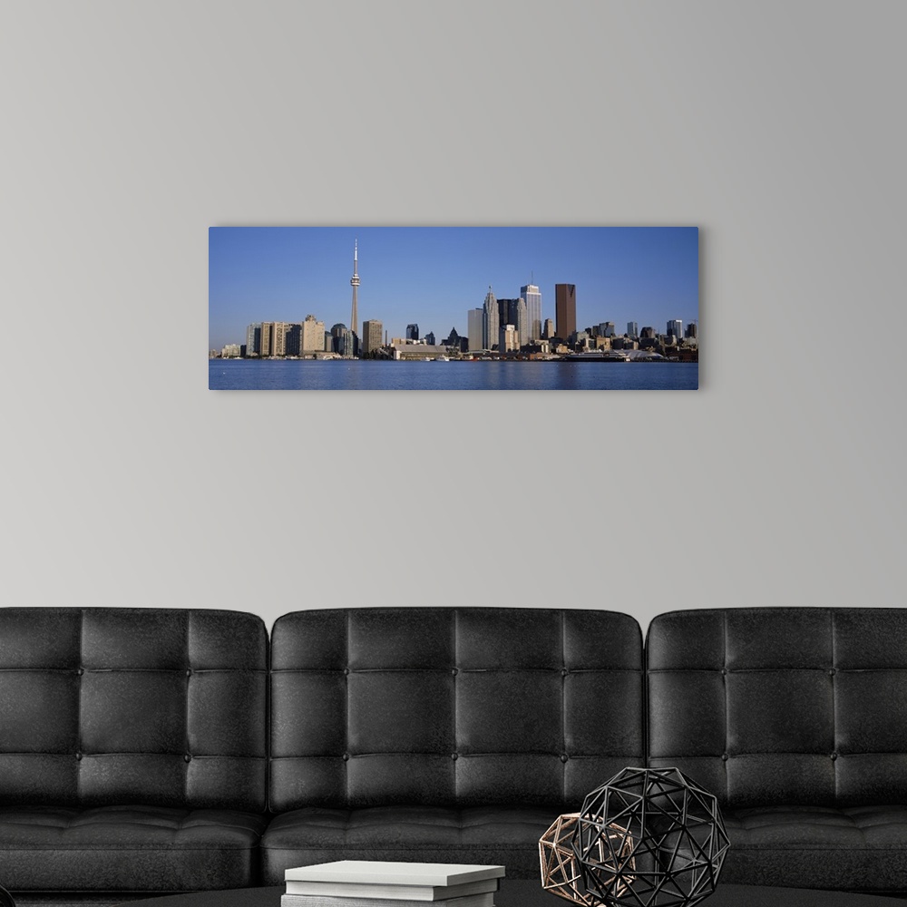 A modern room featuring Panorama of a city skyline of tall modern buildings on the edge of a lake on a sunny day with a c...
