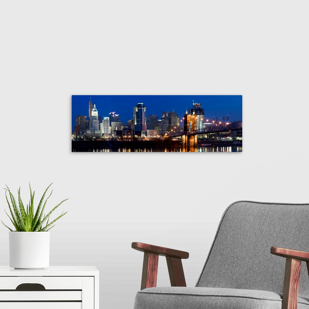 A modern room featuring Tall buildings reflecting in the water of the Ohio River in this panoramic landscape canvas.