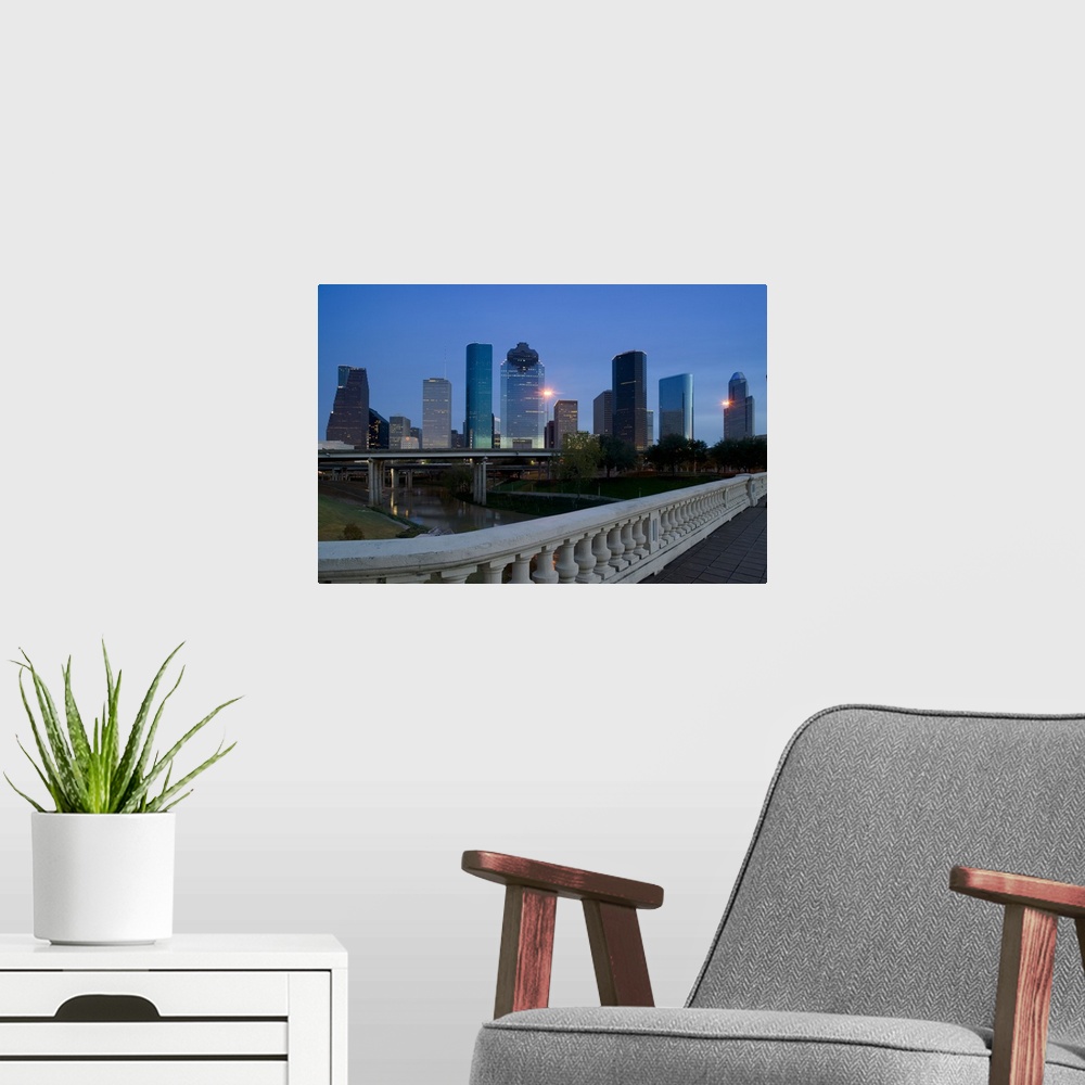 A modern room featuring Street view photograph of tall buildings lit up in a city at dusk.