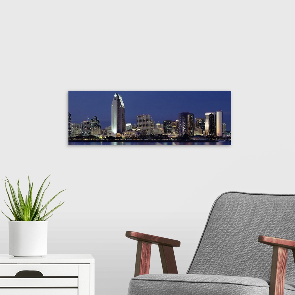 A modern room featuring This large panoramic photograph is of the San Diego skyline at night with all of the buildings li...
