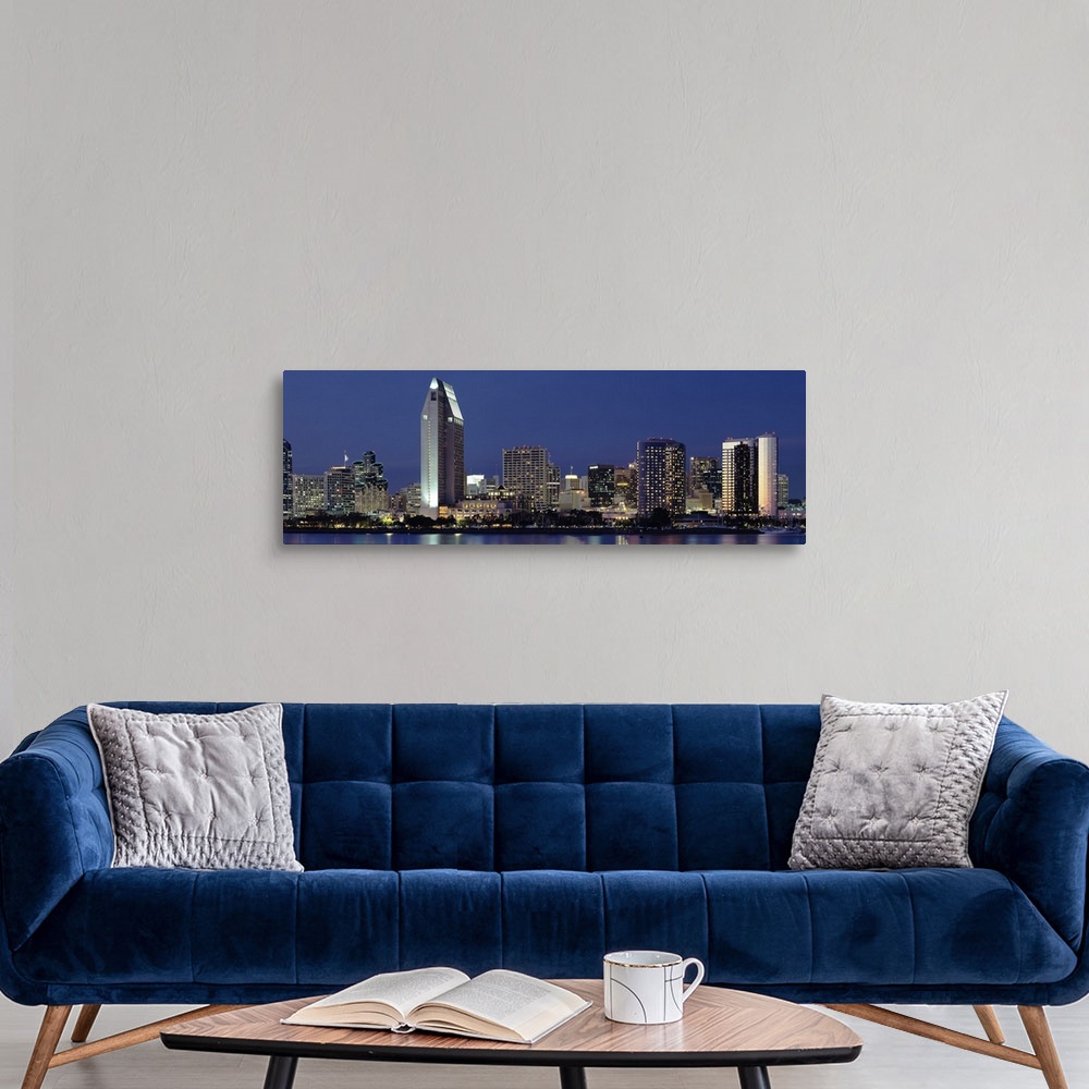 A modern room featuring This large panoramic photograph is of the San Diego skyline at night with all of the buildings li...