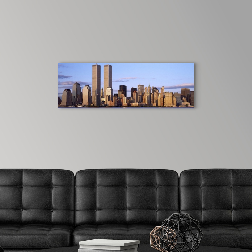 A modern room featuring The Manhattan skyline is photographed in panoramic view with the World Trade Center buildings sta...