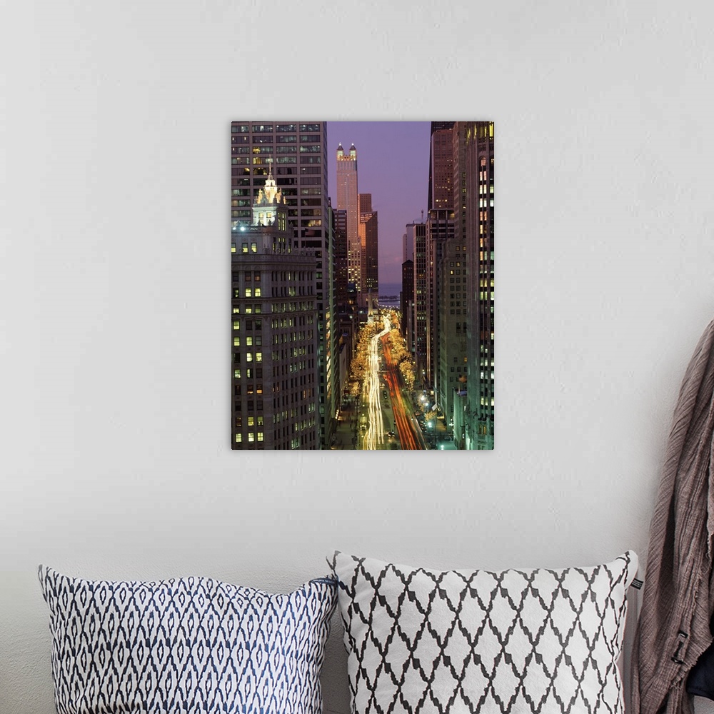 A bohemian room featuring A vertical picture taken in between skyscrapers that line a street in Chicago with cars lights st...