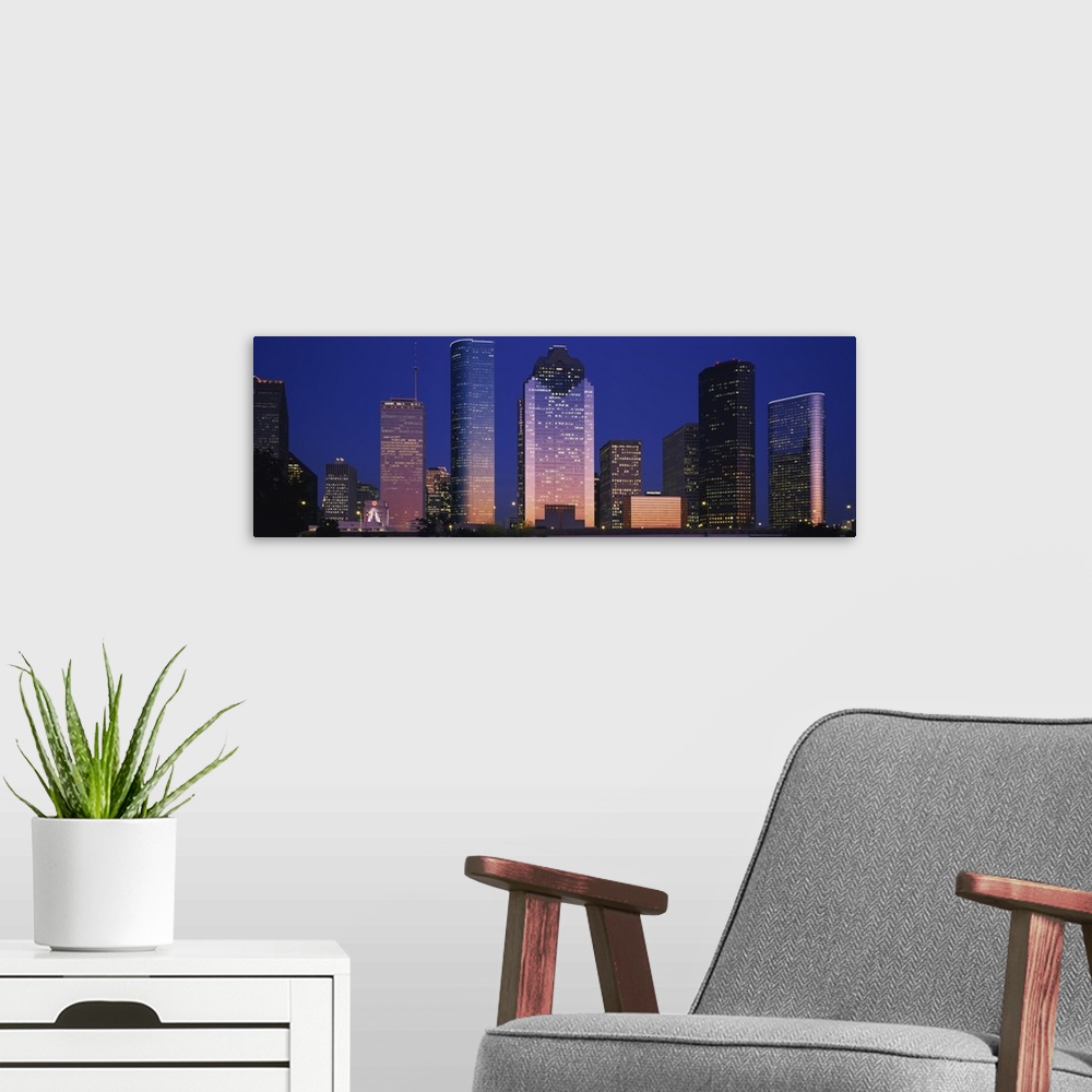 A modern room featuring Large panoramic view of the Houston skyline with the buildings illuminated during the night.