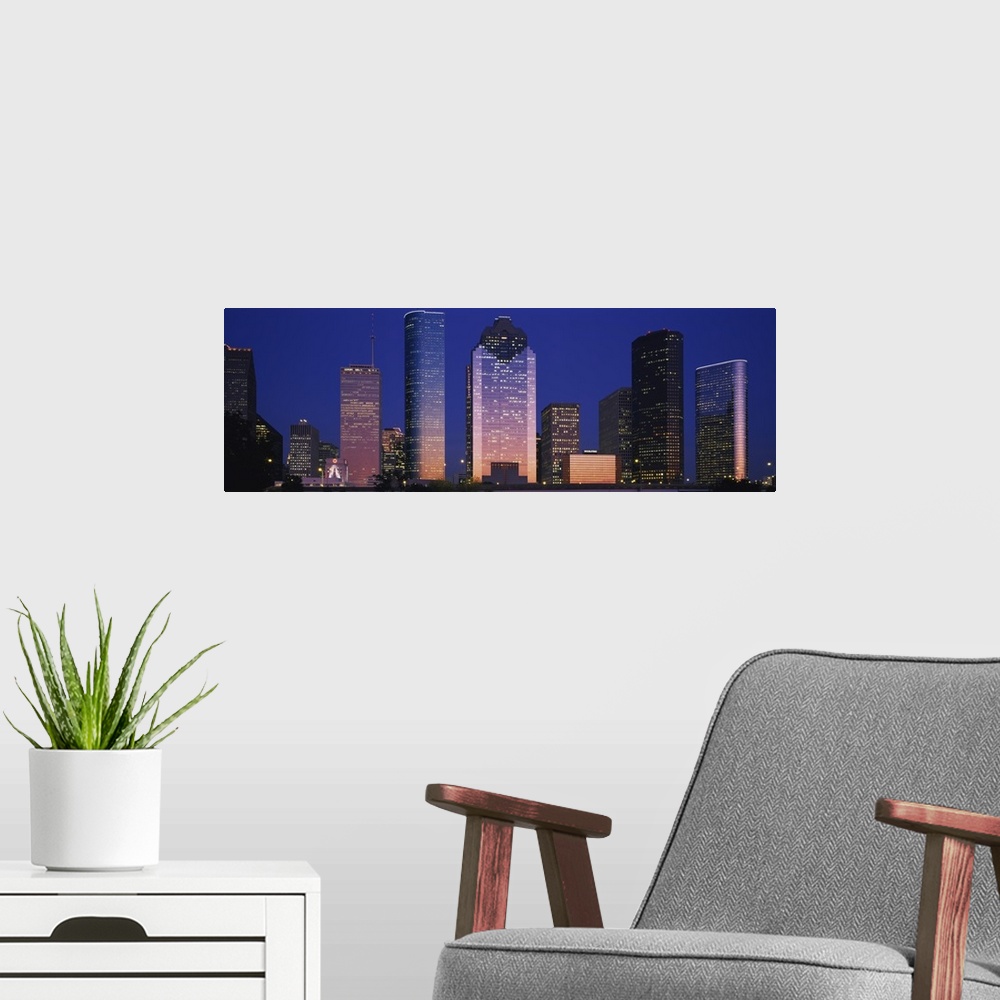A modern room featuring Large panoramic view of the Houston skyline with the buildings illuminated during the night.