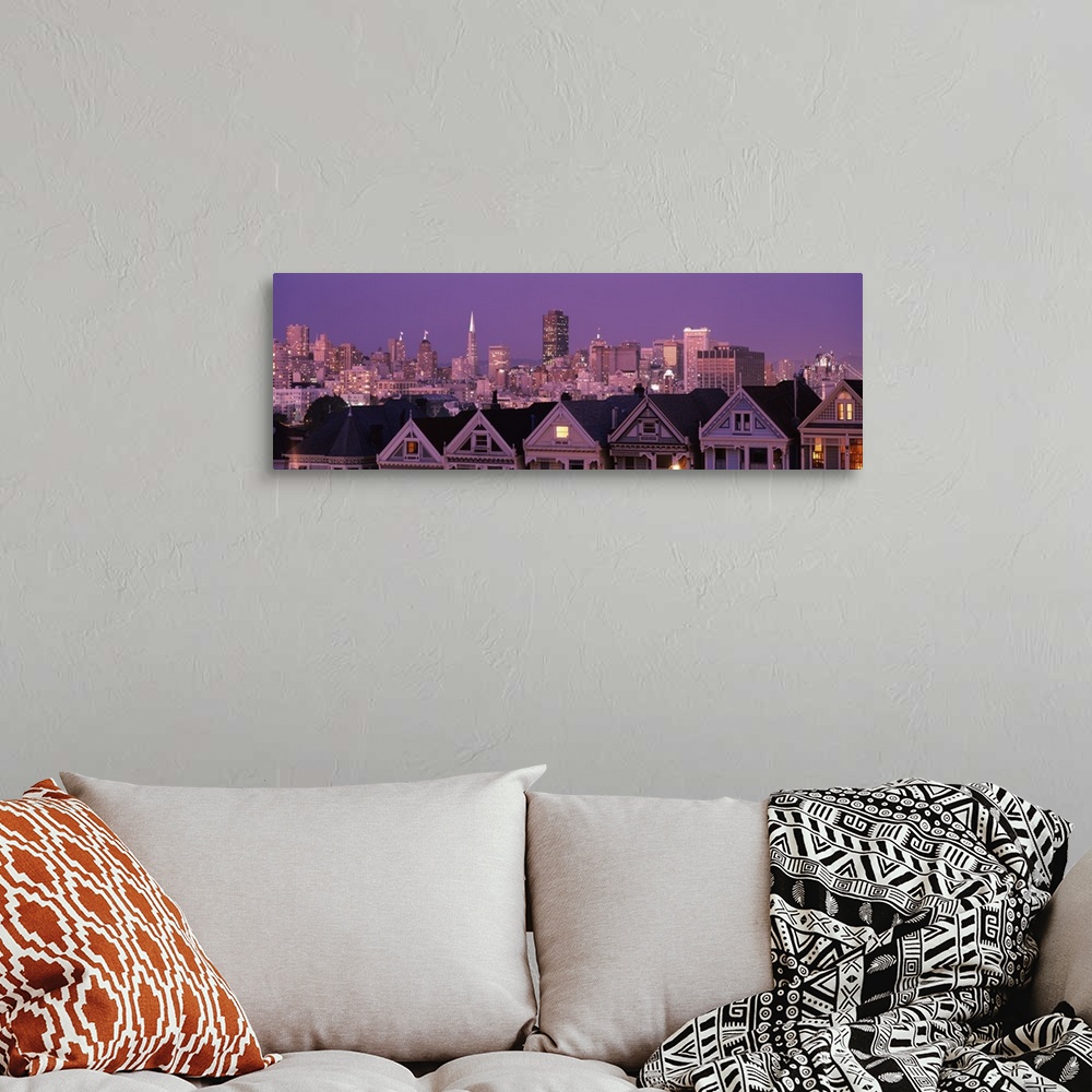 A bohemian room featuring The San Francisco skyline is illuminated at night and photographed in wide angle view from a dist...