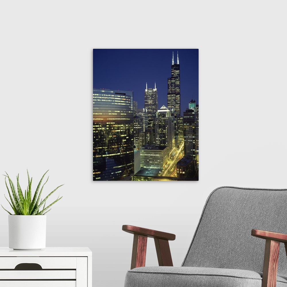 A modern room featuring Vertical, high angle photograph overlooking Wacker Drive in Chicago, surrounded by lit buildings ...