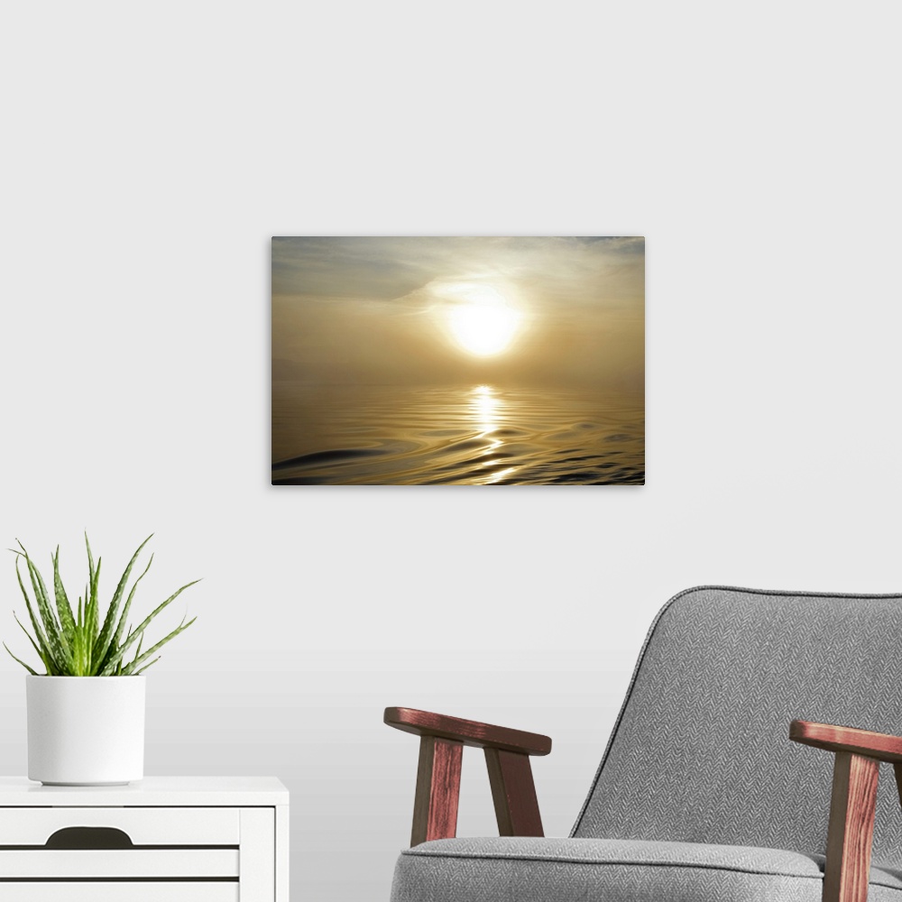 A modern room featuring Large landscape photograph of a rising sun covered by a thin haze in the sky, above the rippling,...