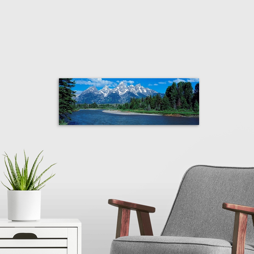 A modern room featuring Panoramic photo of rugged mountains in the background of a wide river cutting through the landsca...