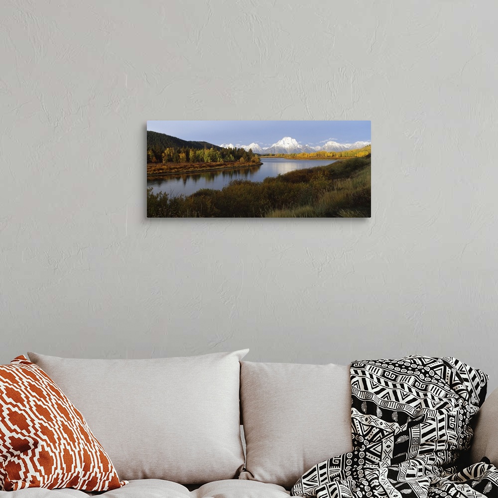 A bohemian room featuring A landscape photograph of a river winding through the meadowlands with snow covered mountain peak...