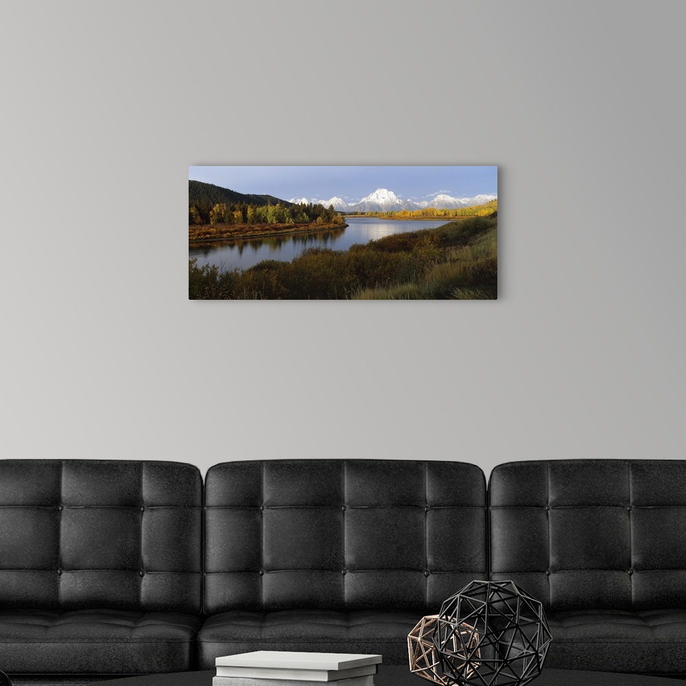 A modern room featuring A landscape photograph of a river winding through the meadowlands with snow covered mountain peak...