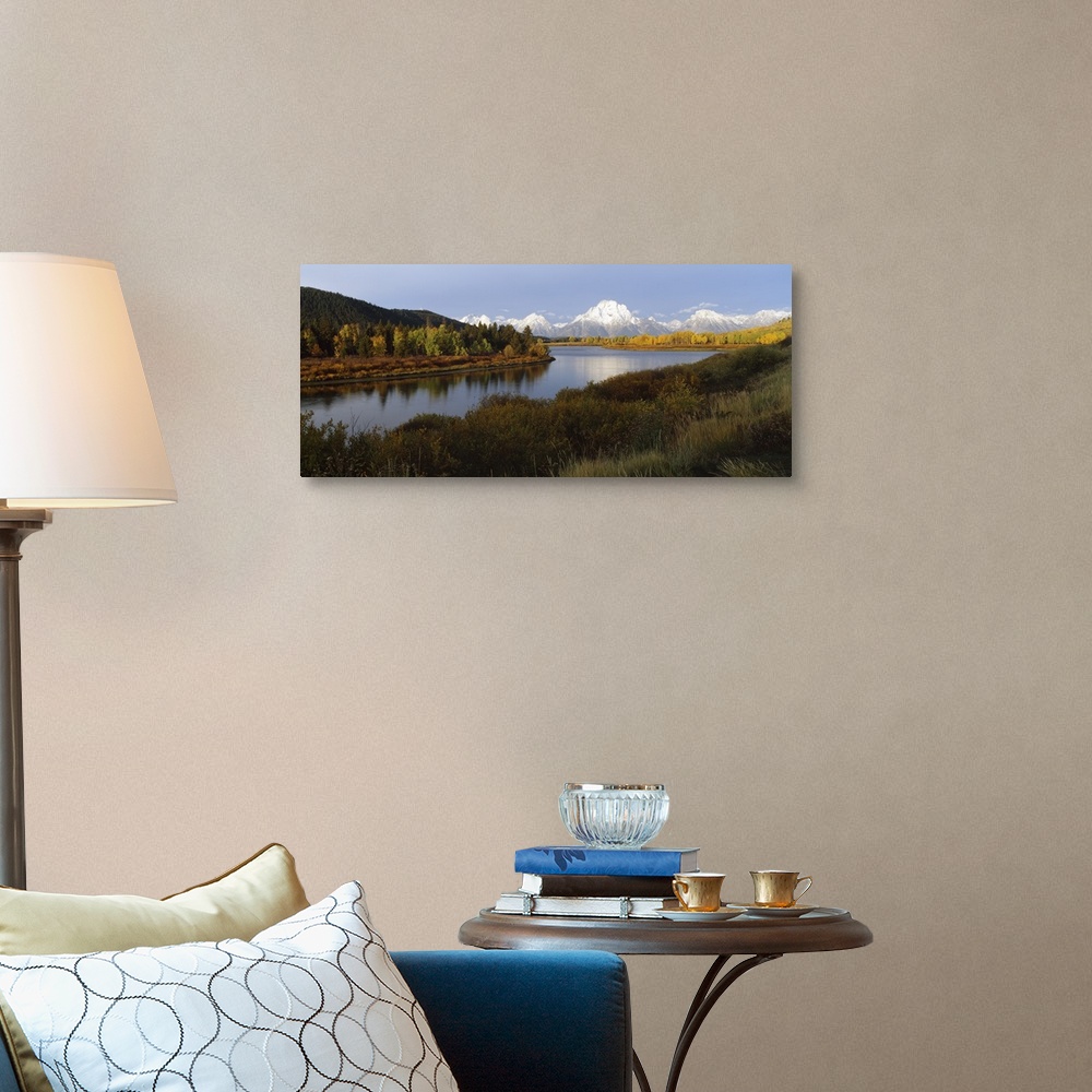 A traditional room featuring A landscape photograph of a river winding through the meadowlands with snow covered mountain peak...