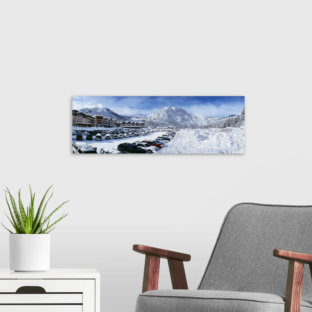 A modern room featuring Snow covers the mountains, ground and cars that sit parked at a large ski resort in Lake Tahoe.