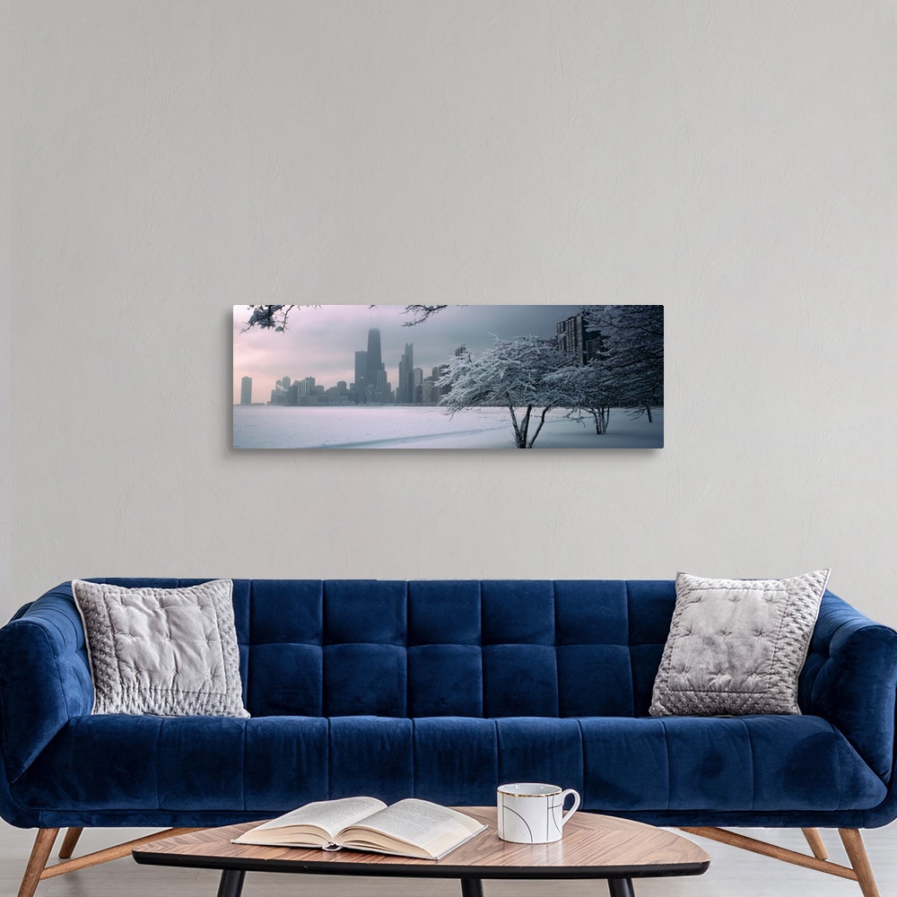 A modern room featuring Panoramic photograph of winter snow on a shore with a city skyline in the distance.  There are tr...
