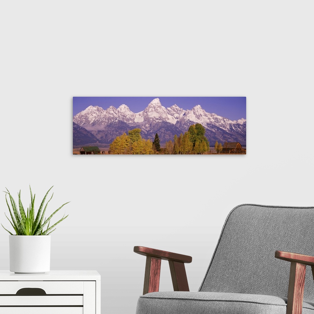 A modern room featuring Panoramic photograph taken of an immense mountain range that has the tops covered with snow. Some...