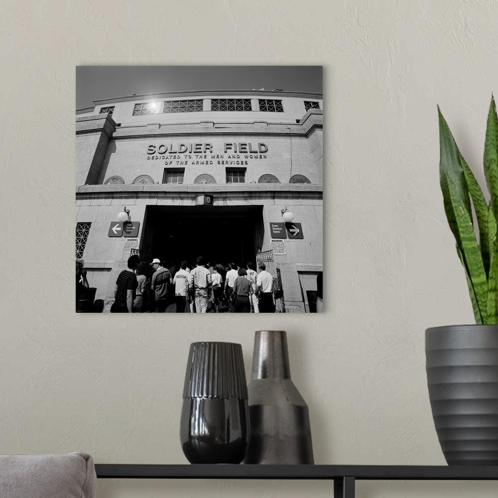 A modern room featuring A black and white photograph of fans entering the Chicago Bears stadium with the fields name disp...