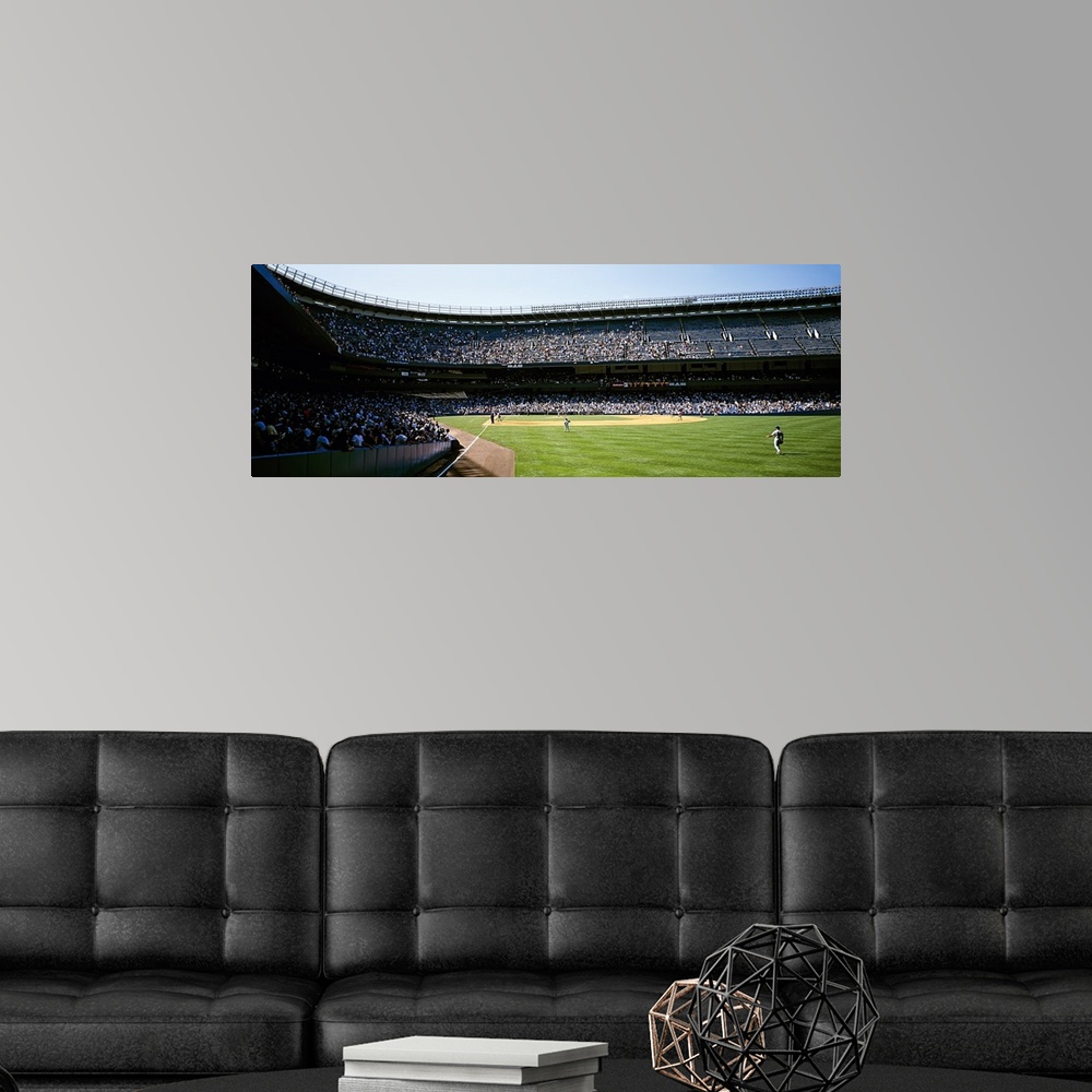 A modern room featuring Wide angle photograph of Yankee Stadium with stands full of fans, during a baseball game in New Y...