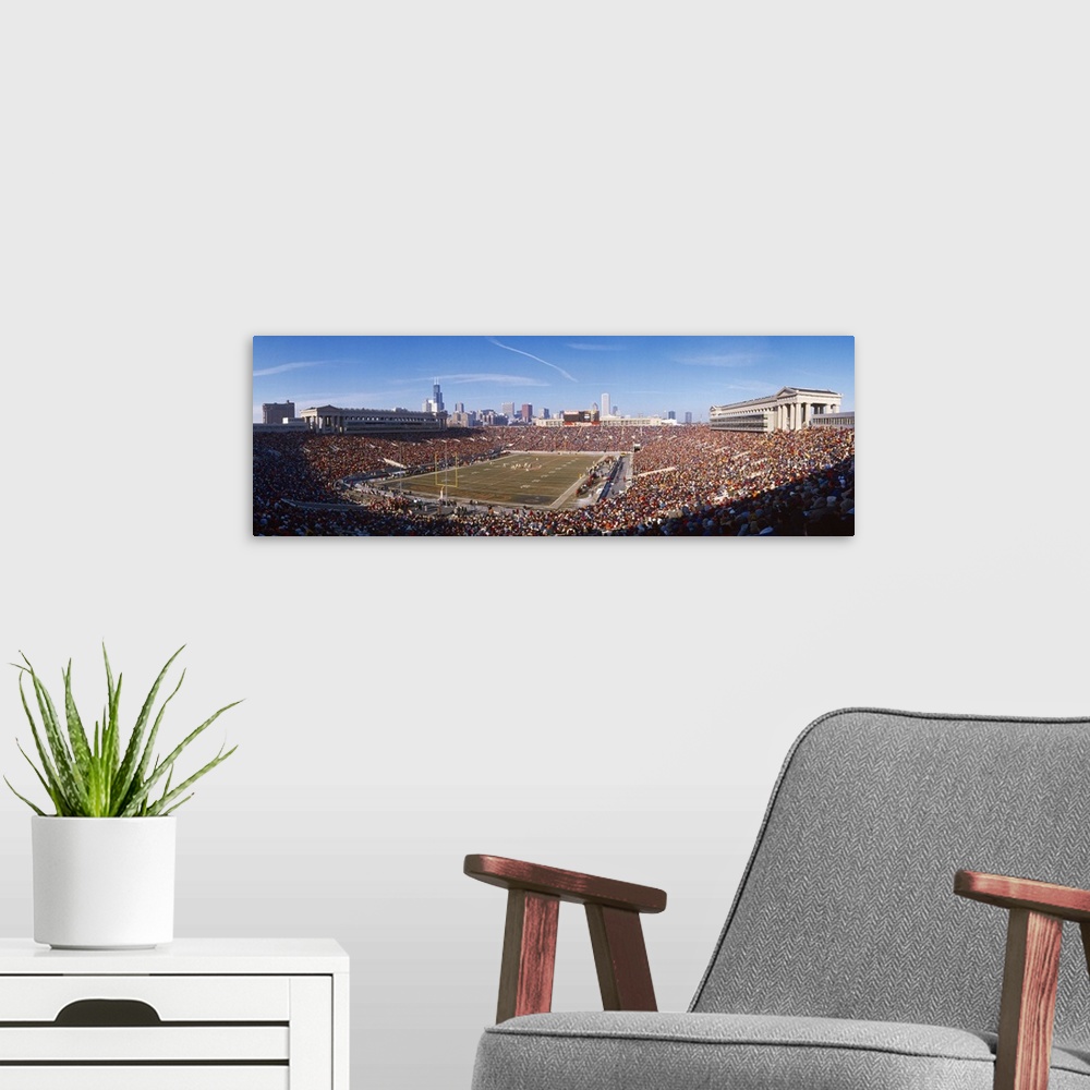 A modern room featuring A crowded stadium full of sports fans ready to watch the Chicago Bears game under a clear blue sk...