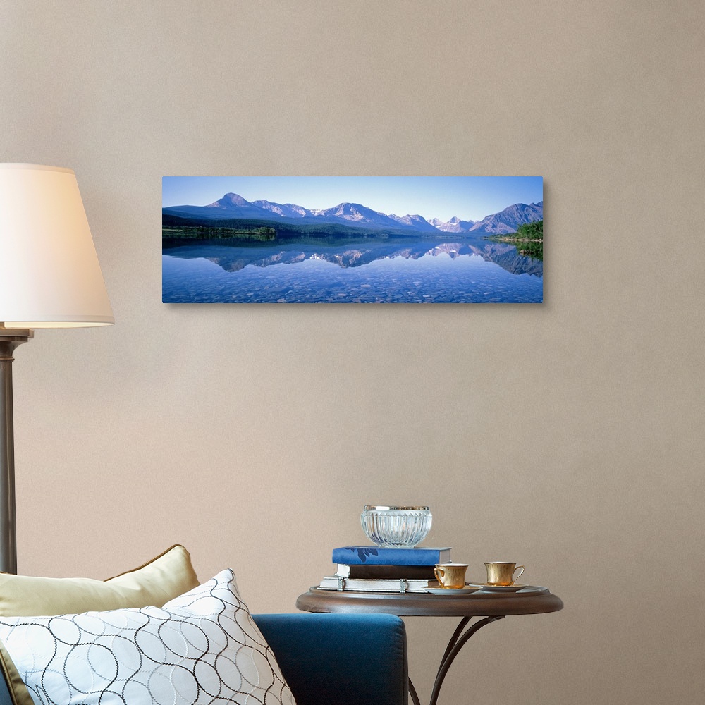 A traditional room featuring Mountains line the back of this panoramic photograph that is taken from across a crystal clear la...