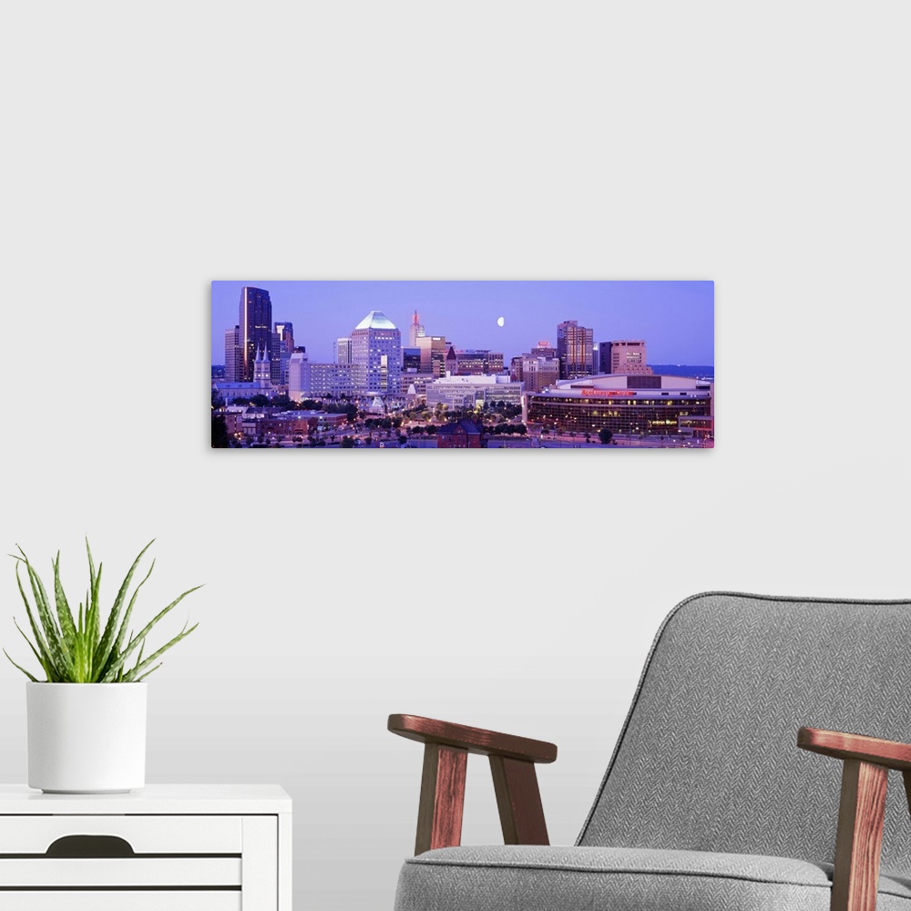 A modern room featuring Panoramic photograph of skyline lit up at dusk with moon in the sky.