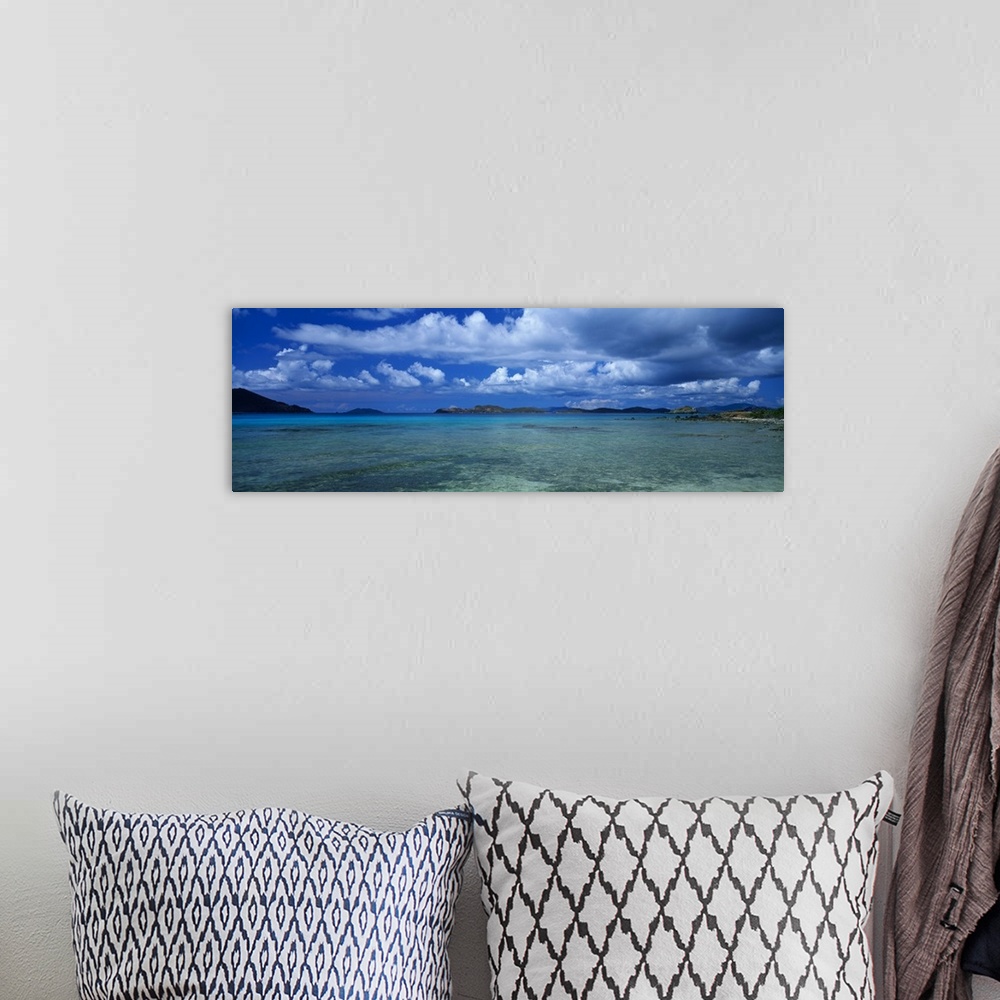 A bohemian room featuring A breathtaking photograph of teal ocean water with large clouds in the sky that hang over.