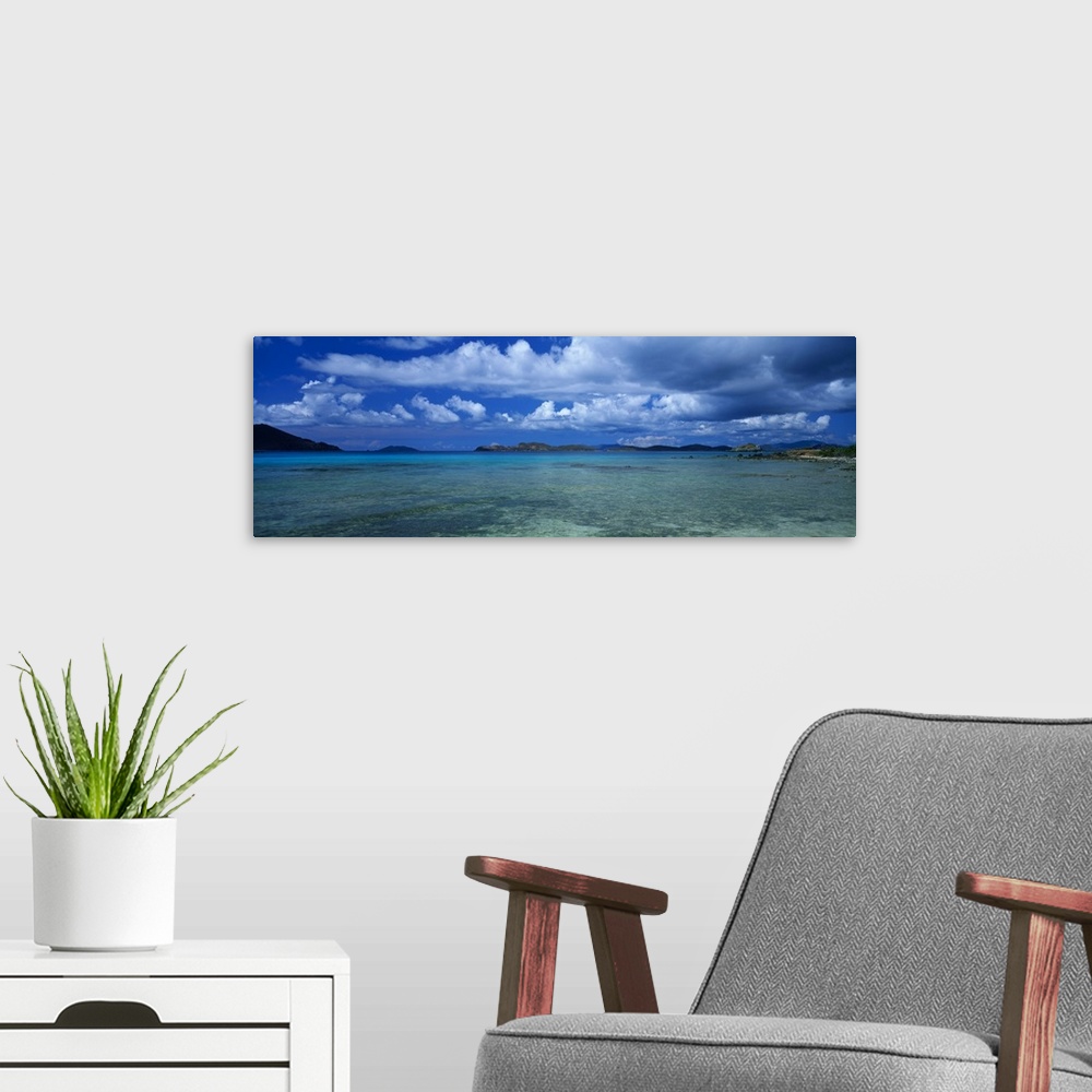 A modern room featuring A breathtaking photograph of teal ocean water with large clouds in the sky that hang over.