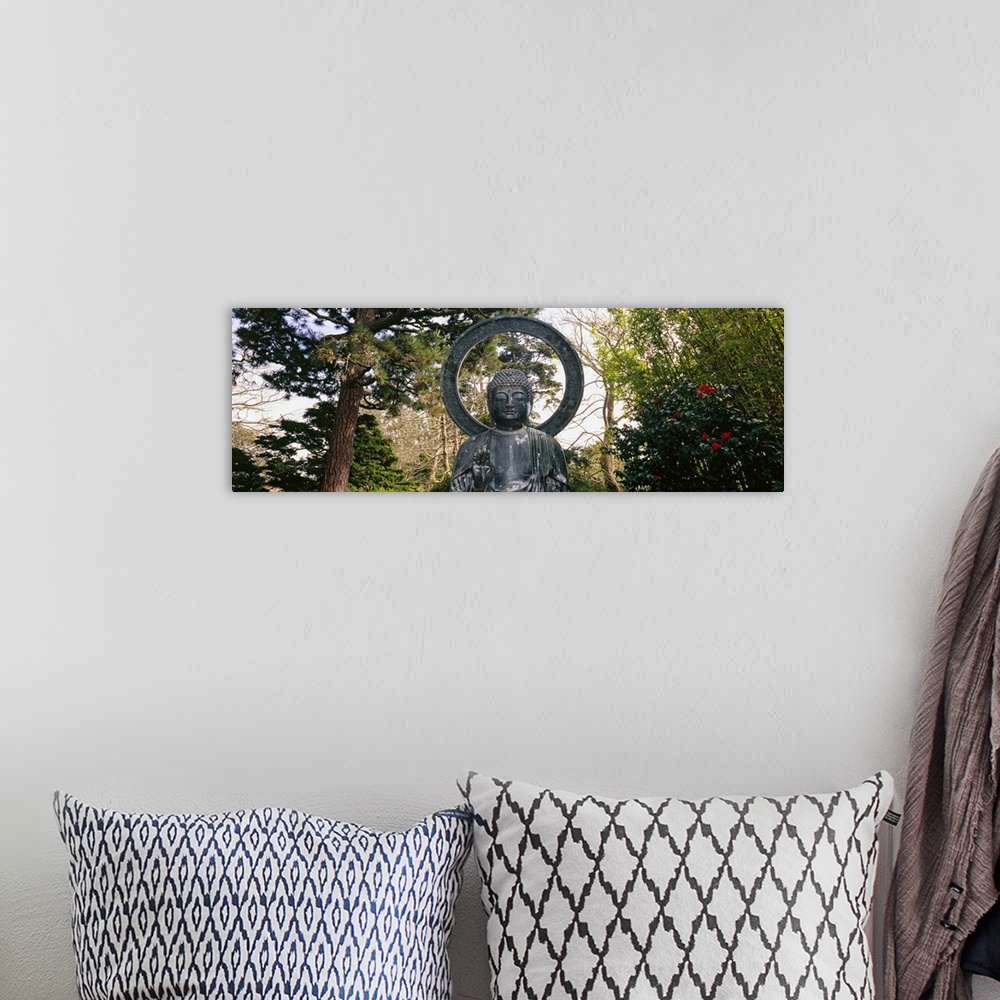 A bohemian room featuring This Buddha statue is pictured as a panorama with trees scattered about in the background.