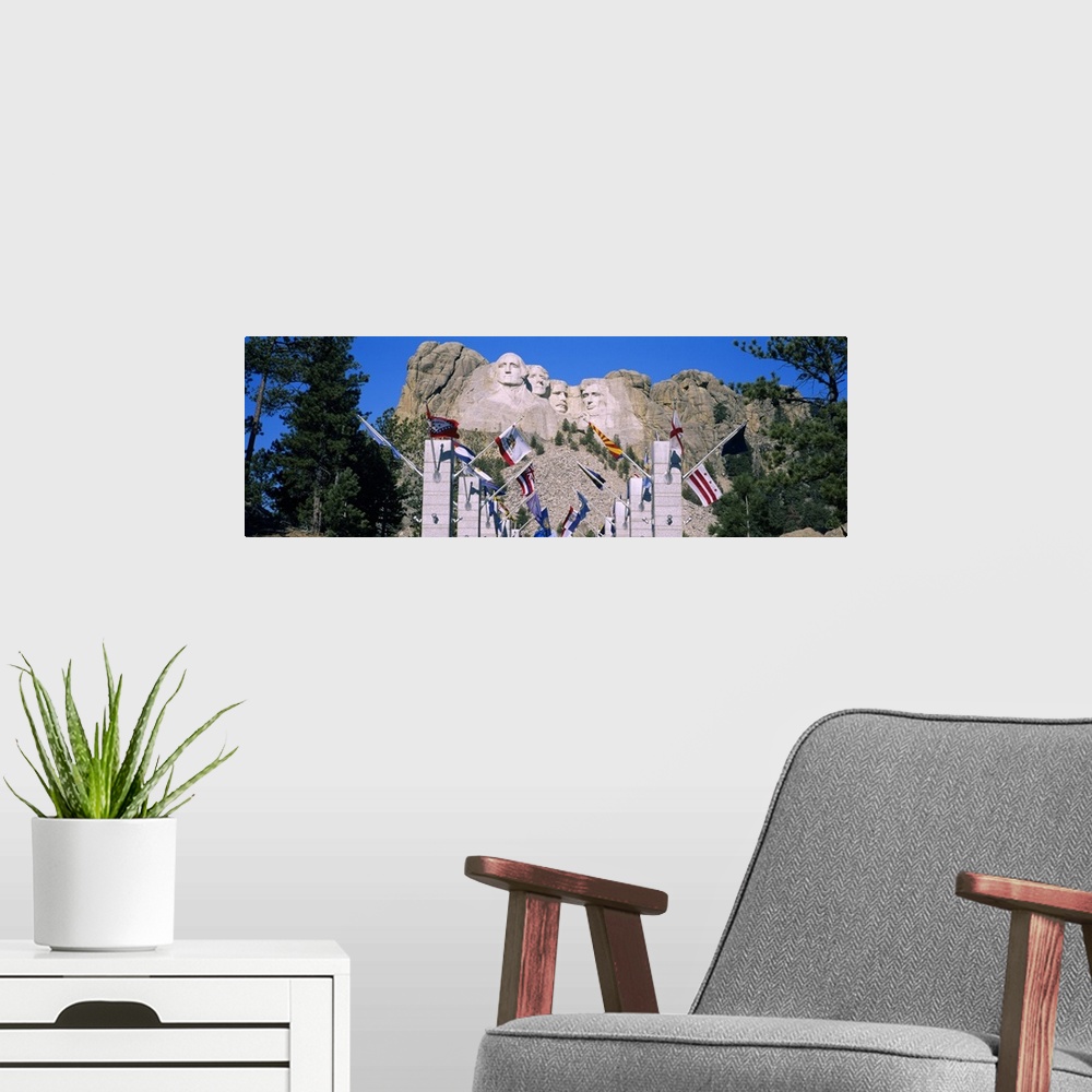 A modern room featuring Panoramic photograph of iconic stone memorial carved in mountainside with column and flag lined w...
