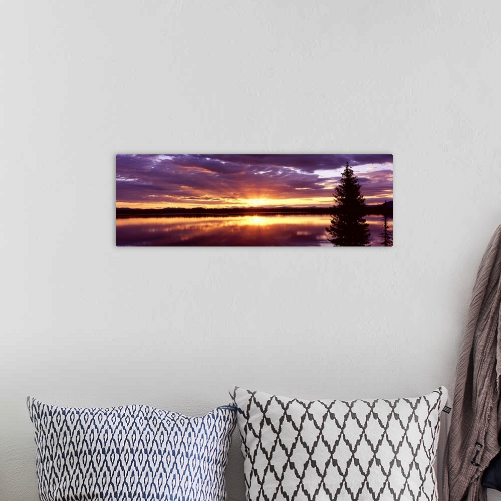 A bohemian room featuring Long horizontal canvas of the sun rising through stormy clouds reflected onto the lake.
