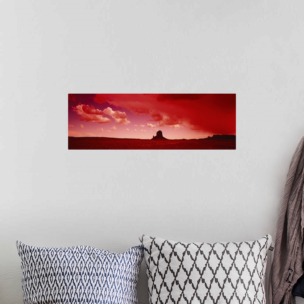 A bohemian room featuring Giant horizontal photograph of a desert landscape beneath a vibrant sky with billowing clouds, a ...