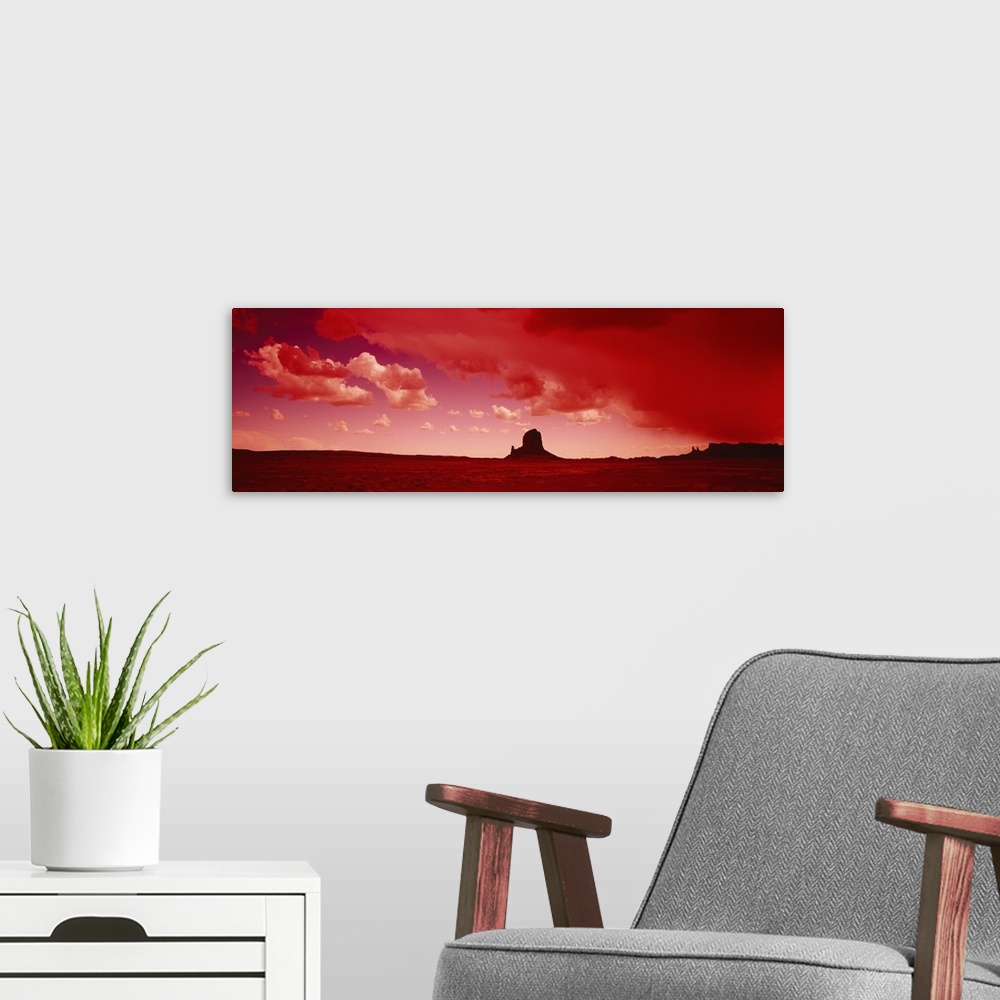 A modern room featuring Giant horizontal photograph of a desert landscape beneath a vibrant sky with billowing clouds, a ...