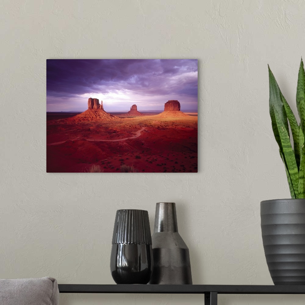A modern room featuring Big photograph shows a barren desert landscape within the Southwestern United States as three gig...