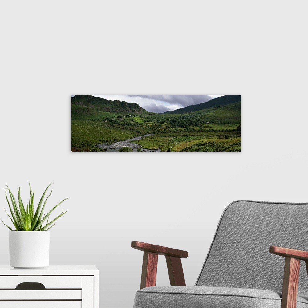 A modern room featuring Stream through lush mountain landscape, distant cottages, Ireland