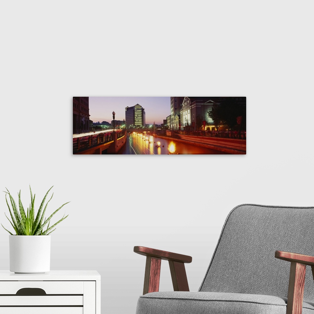 A modern room featuring Panoramic canvas photo of lights along a road that leads to buildings in a city at sunset.