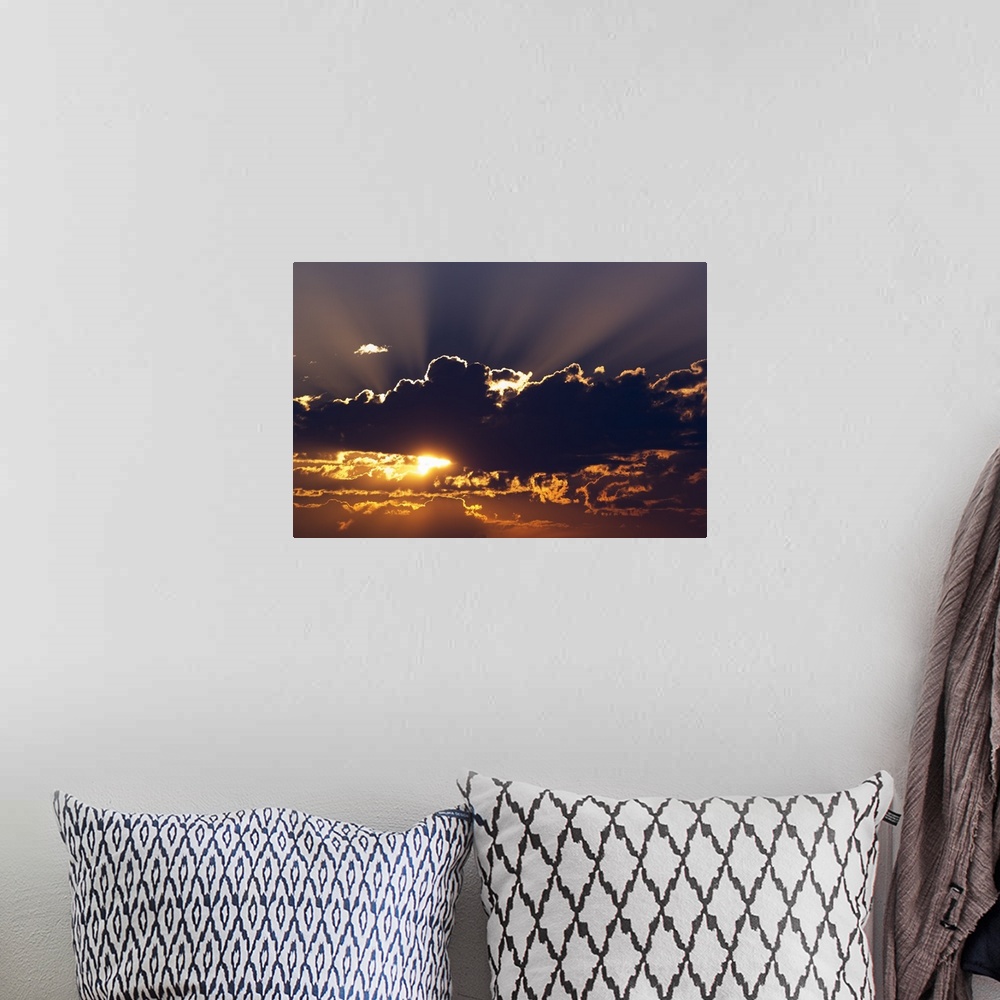 A bohemian room featuring Big canvas photo of the sun peeking through dark clouds.