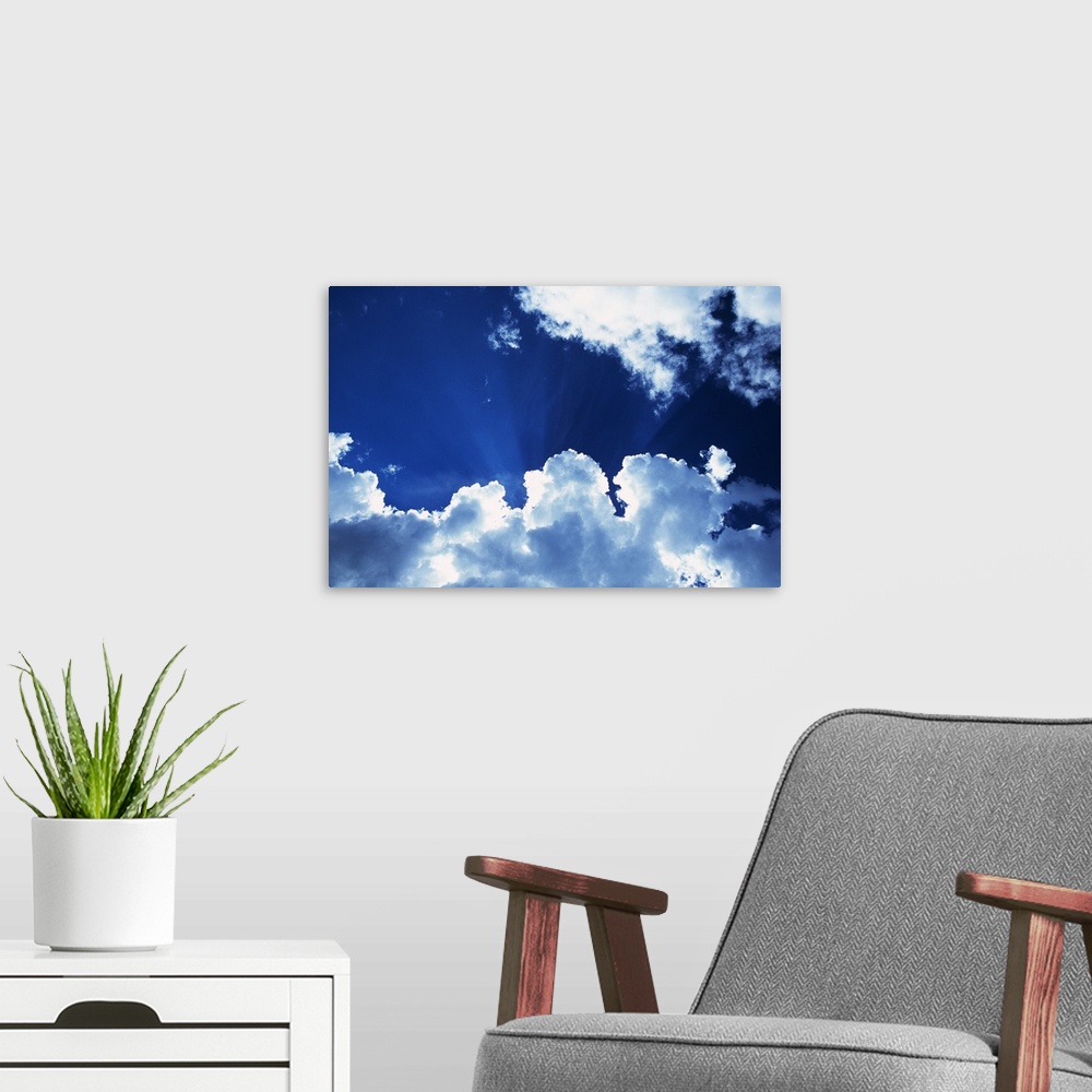 A modern room featuring Sunbeams behind billowing white clouds, blue sky.